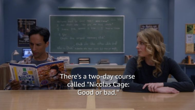 Abed and Britta from the tv show Community sit at a table. Britta is facing Abed, and Abed is looking through a catalog. The words "There's a two-day course called 'Nick Cage: Good or Bad'' runs along the bottom.