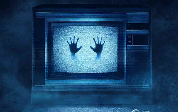 A still from the movie Poltergeist: an old school tube tv in a misty dark background. The screen is filled with snow, and two hands press into the snow from inside the television.