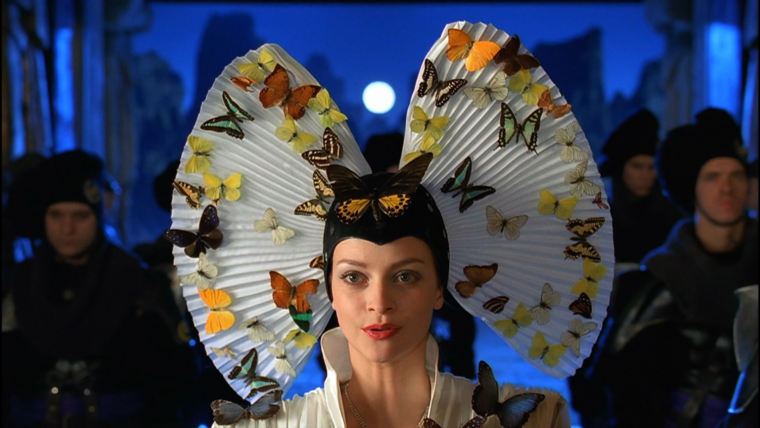 A headshot of Princess Irulan fron the SyFy Dune miniseries wearing a big fanned headdress with butterflies all over it.