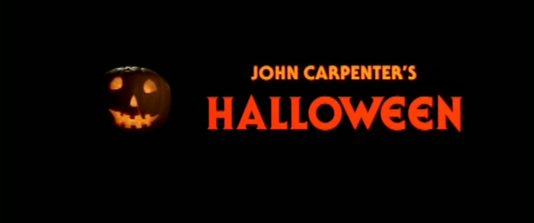 black background with the words "John Carpenter's Halloween" written in orange. To the side, there is a a jack o' lantern with the face lit up.
